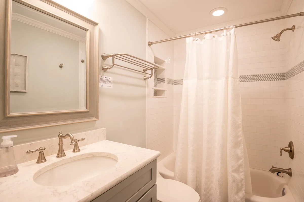 Features a modern bathroom with a vanity, sink, mirror, and a visible shower area. The space feels serene and inviting—ideal for personal grooming or a relaxing shower after a day by the sea.