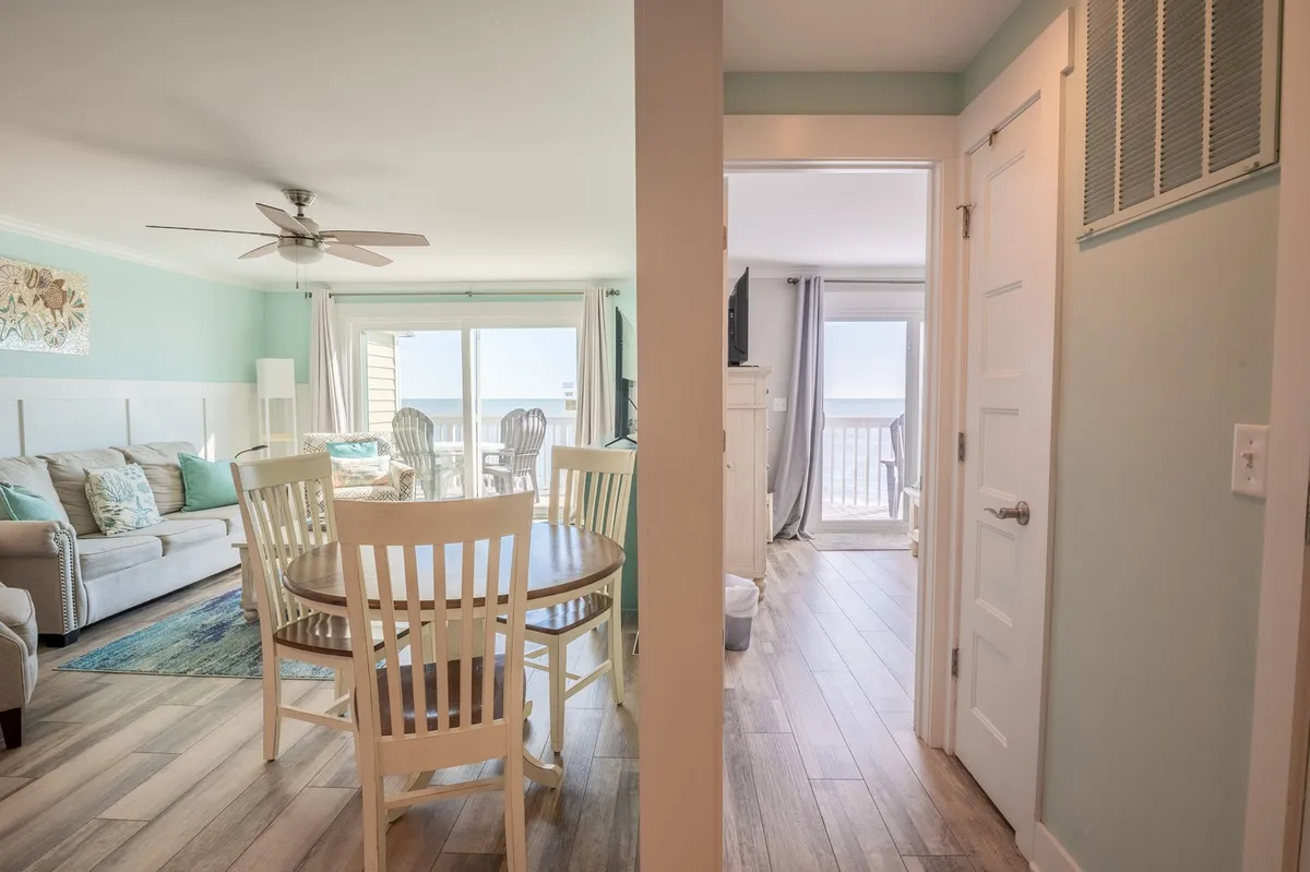 A cozy dining area seamlessly integrated with a comfortable sofa and large windows letting in abundant light. The scene suggests relaxed meals, game nights, and gathering with friends or family, all while enjoying glimpses of the scenic outdoors.