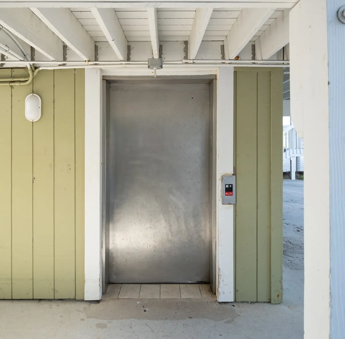 This image features an elevator with a visible control panel and a green accent wall, capturing the practical convenience for guests transporting luggage or needing easier access to the condo. The setting highlights the modern and user-friendly aspect of the property.