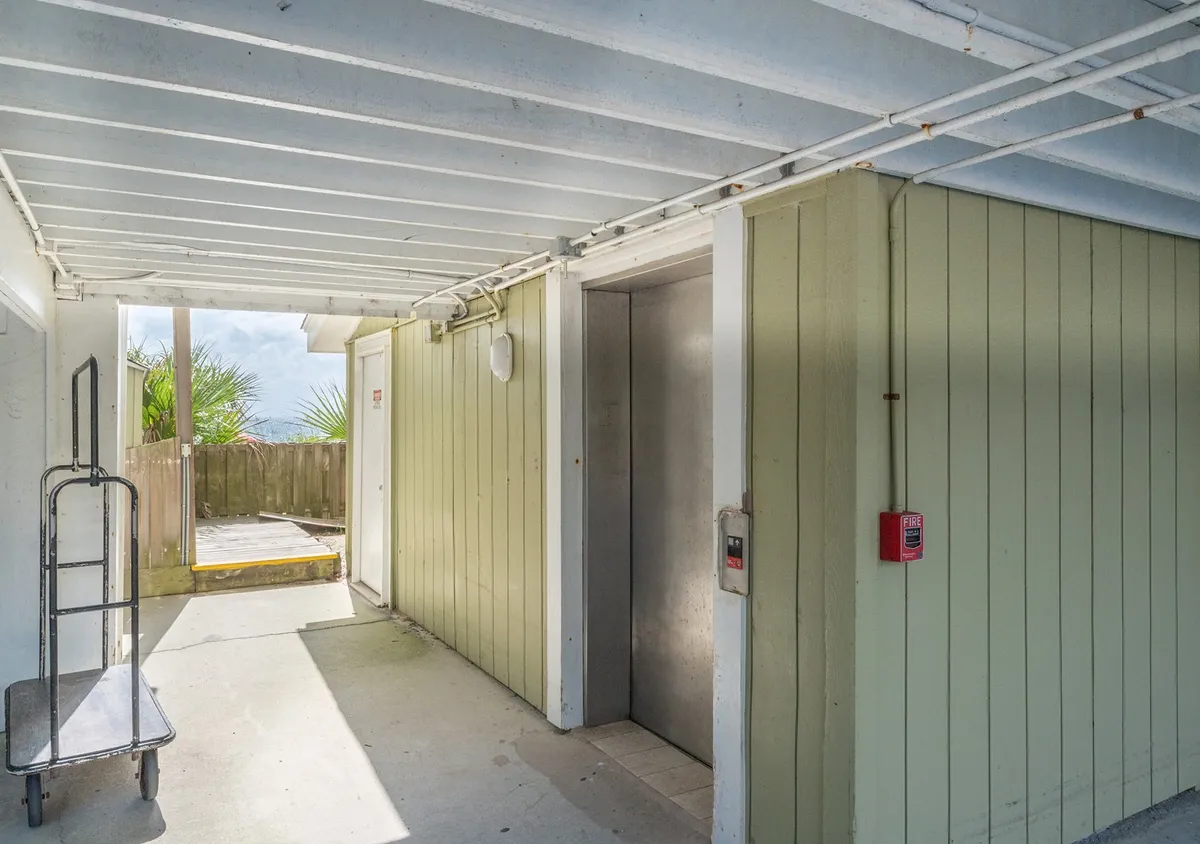 Showing the elevator lobby area with a trolley cart and green wall, this practical space demonstrates the ease of moving luggage and accessing upper floors. The scene is uncluttered and signals the thoughtful amenities provided for smooth arrivals.